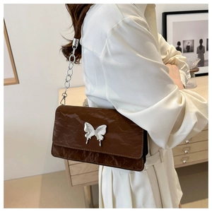 Close-up of vintage brown leather shoulder bag featuring a silver butterfly metal buckle