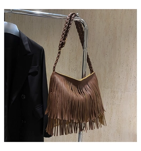 Detail of brown tasseled shoulder bag with woven strap and pebbled leather texture