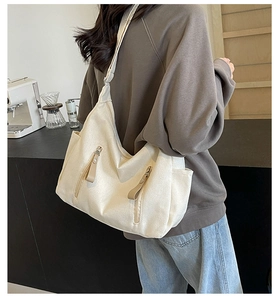 Detail van grote crème canvas crossbodytas met twee verticale ritszakken voor dagelijks