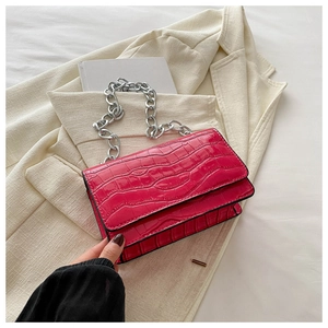 Detail of vibrant magenta faux crocodile leather bag with chunky silver chain strap