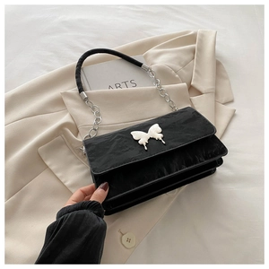 Detail of black pleated shoulder bag with white butterfly buckle and accordion layers