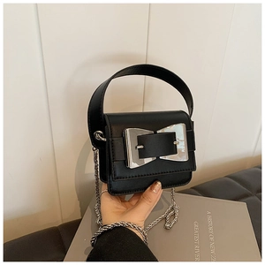 Detailed view of black leather handbag with silver metal bow buckle and chain strap