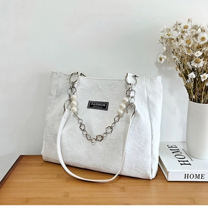 Détail du cabas blanc à fleurs avec chaîne de perles et étiquette fashion instinct