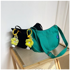Détail des sacs bandoulière en toile verte et noire avec breloques de tournesol