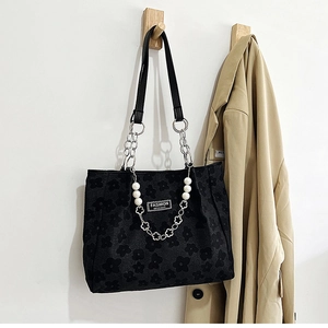 Détail du cabas en jacquard noir gaufré avec chaînes métalliques et breloques en perles