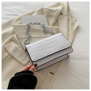 Close-up of white crocodile pattern crossbody bag with silver metal chain on a blazer