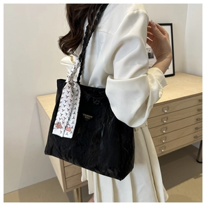 Detailopname van zwarte shopper met gevlochten riem en decoratieve sjaal voor dames
