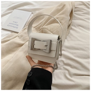 Detail of white mini crossbody bag featuring a large silver bow-shaped metal buckle buckle