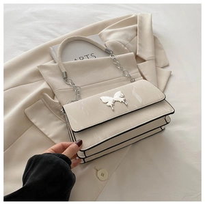 Detail of cream shoulder bag with silver butterfly buckle and layered accordion structure