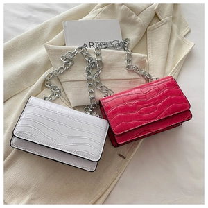 Detail showing white and magenta crocodile texture crossbody bags with silver chain straps