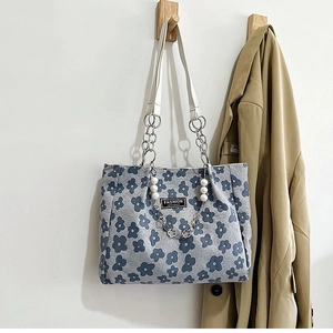 Détail d'un cabas floral avec poignée en cuir blanc et pendentif décoratif en perles