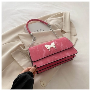 Pink shoulder bag with silver butterfly charm and marble texture on white suit jacket