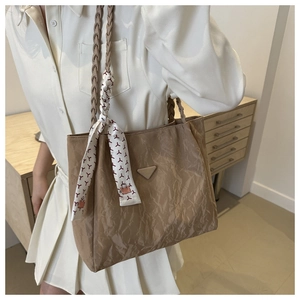 Detail van kaki geplooide shopper met gevlochten handvat en zijden sjaal accessoire