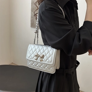 Silver quilted chain bag with metal bow detail worn by a model on shoulder