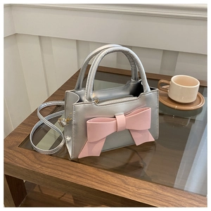 Detailed view of silver PU leather crossbody bag with oversized pink bow and gold zipper