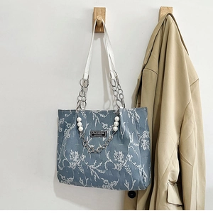 Détail du tissu jacquard floral avec chaîne de perles et poignée en cuir blanc
