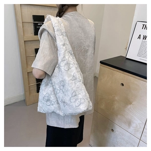 Detail view of large white tote bag with textured butterfly pattern and wide strap