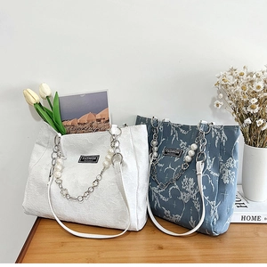 Gros plan de sacs cabas en toile imprimée avec bandoulière en perles et détails métal
