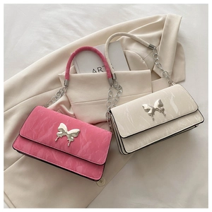 Detail of trendy metallic butterfly buckles on pleated pink and beige shoulder bags
