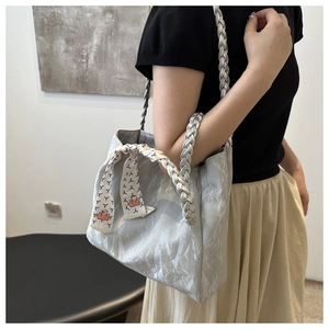 Detail van zilveren shopper met metallic plooistructuur en gevlochten handvat met sjaal