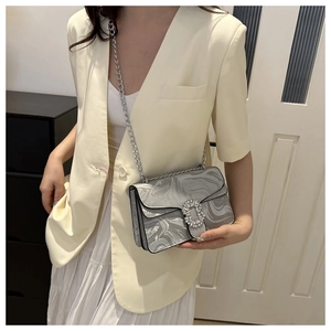 Detail of silver marble pattern shoulder bag with a large sparkling rhinestone buckle