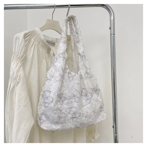 Detail of white canvas tote featuring 3D butterfly embroidery and fringe texture