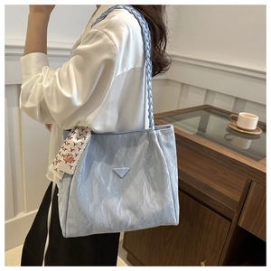 Detail van een lichtblauwe shopper met geweven band en decoratieve zijden sjaal