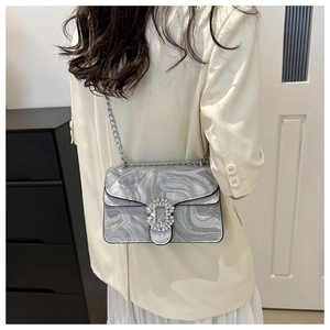 Detail of grey marble texture crossbody bag with crystal buckle worn with a beige suit
