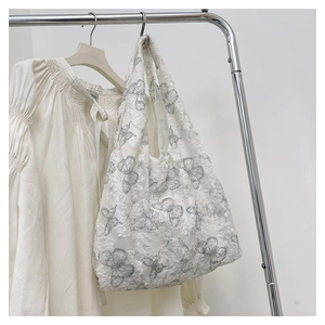 Detail of white tote bag featuring 3D butterfly embroidery and floral mesh texture