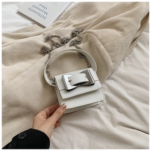 Macro shot of white leather mini crossbody bag with silver buckle and metal chain strap
