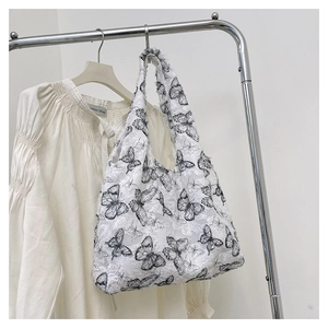 Detail of white tote bag featuring black butterfly embroidery on soft lace fabric texture