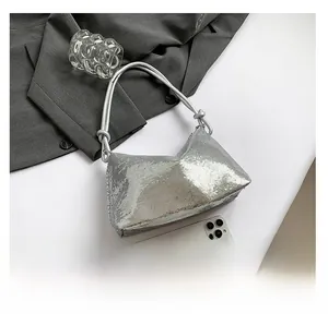 Macro shot of silver sequin hobo bag with size comparison next to a smartphone