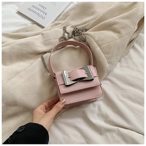 Close-up of pink crossbody bag with silver square metal buckle on textured background