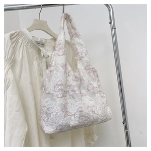Detail of white lace tote bag with purple butterfly patterns on a metal hanger
