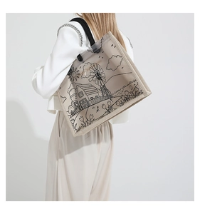 Detail of PVC tote bag with farm pattern printing and canvas trim on woman's shoulder
