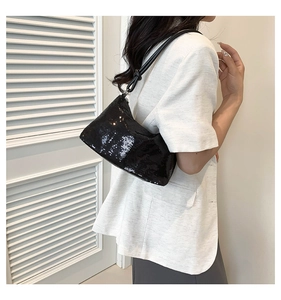 Detail view of black sequin underarm bag with decorative knot strap for evening wear