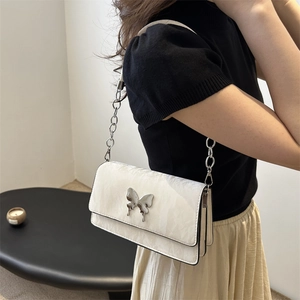 White minimalist shoulder bag with silver butterfly hardware and chain strap on model