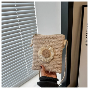 Detail of hand-woven straw crossbody bag featuring a large daisy floral applique