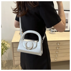 Detail of silver crescent buckle on a metallic faux leather handbag with shoulder strap