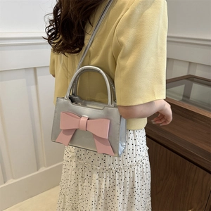 Silver metallic leather crossbody bag featuring a large decorative pink bow for women