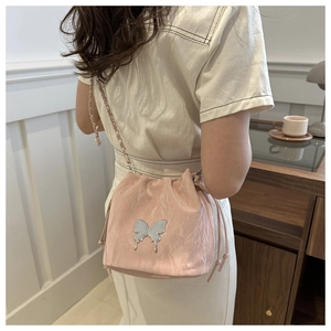 Detailed close-up of a pink pleated bucket bag featuring a silver butterfly charm and chain