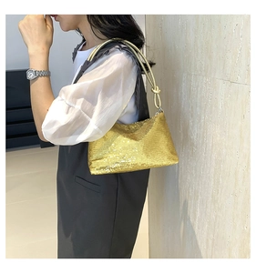 Detail of gold sequin underarm bag with decorative knot and metallic tube strap