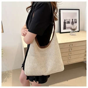 Sac fourre-tout tissé bohème avec bordure en cuir marron porté à l'épaule dans un décor
