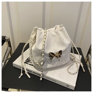 Detail of white lychee leather bucket bag with golden butterfly and drawstring