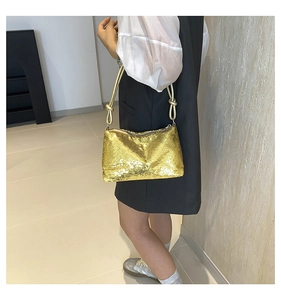 Close-up of golden sequins on women's handbag with elegant knotted rope shoulder strap