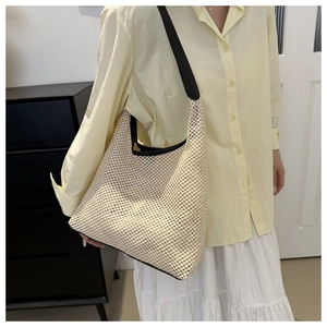 Détail d'un sac cabas en maille tissée beige avec bordure noire et bandoulière large