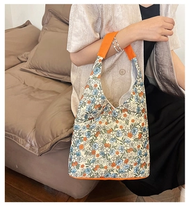 Gros plan du sac cabas à fleurs montrant les motifs bleus et les anses oranges