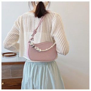 Detailed back view of pink crescent bag with pearl heart chain on a model outfit