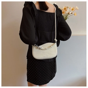 Detail of cream white faux leather shoulder bag with pearl heart chain and long strap