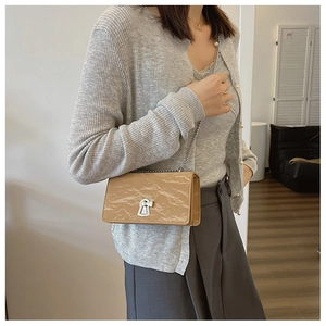 Detailed shot of beige crossbody bag with textured leather and silver clasp on a model